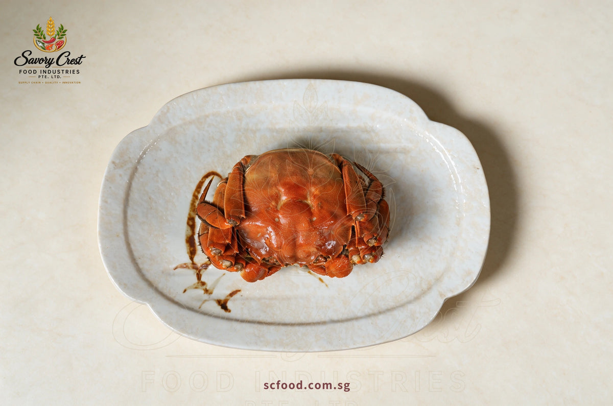 Overhead view of a whole Huadiao drunken hairy crab centred on a cream ceramic platter.